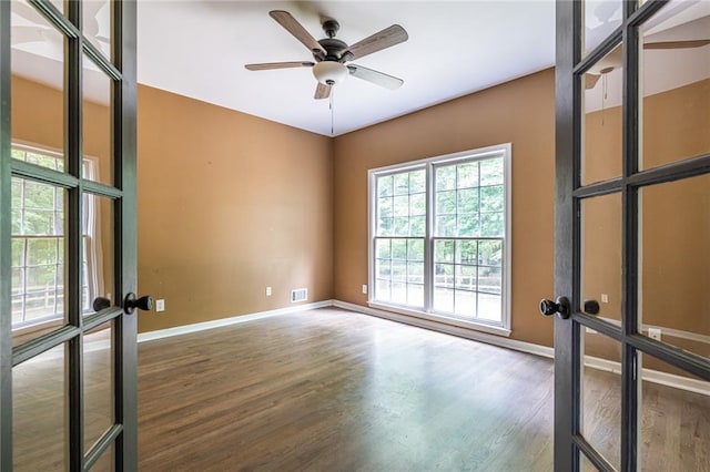 empty room with wood finished floors, baseboards, french doors, and a ceiling fan