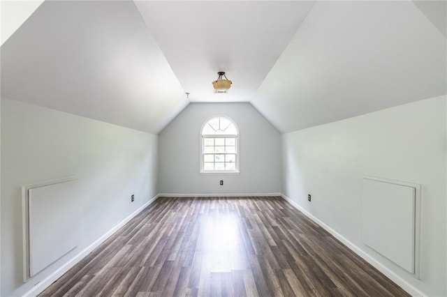 additional living space with vaulted ceiling, dark wood-style floors, and baseboards