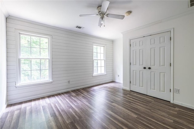 unfurnished bedroom featuring baseboards, dark wood-type flooring, crown molding, a closet, and a ceiling fan