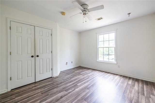 unfurnished bedroom featuring wood finished floors, a closet, baseboards, and ceiling fan