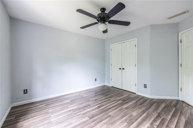 unfurnished bedroom featuring wood finished floors, baseboards, a closet, and ceiling fan