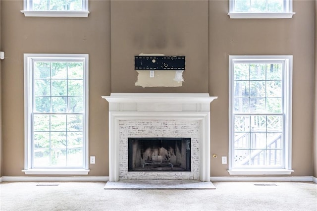 detailed view of carpet, a fireplace with raised hearth, and baseboards