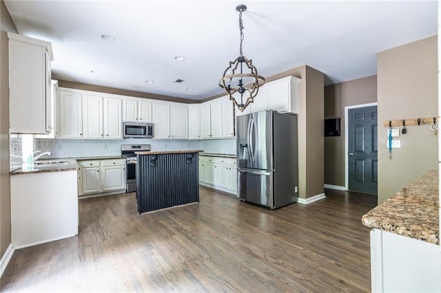 kitchen with appliances with stainless steel finishes, a sink, decorative backsplash, a center island, and baseboards