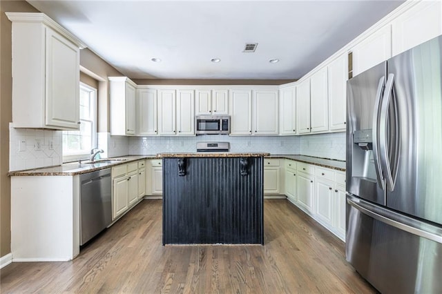kitchen featuring appliances with stainless steel finishes, dark wood finished floors, decorative backsplash, a center island, and recessed lighting