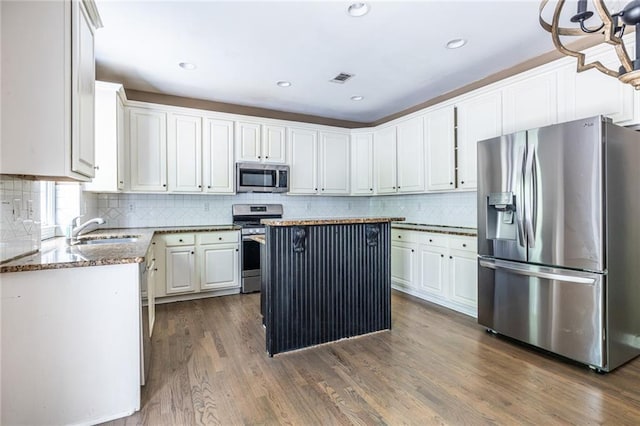 kitchen featuring stainless steel appliances, a sink, white cabinets, backsplash, and dark wood-style flooring