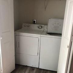 clothes washing area featuring laundry area, dark wood finished floors, and washing machine and clothes dryer