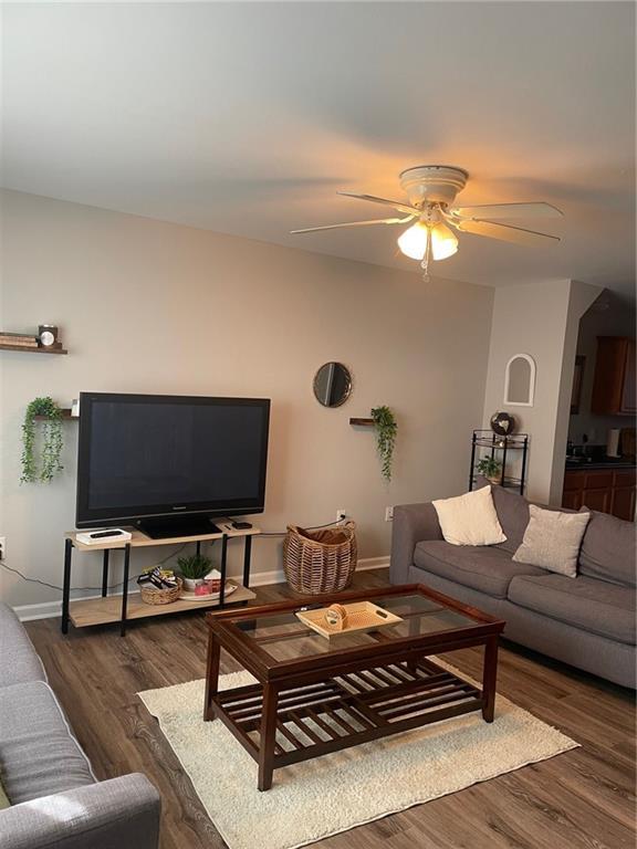 living area with a ceiling fan, baseboards, and wood finished floors