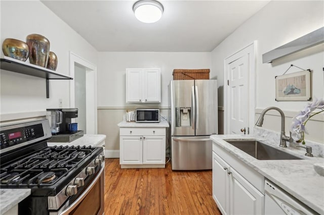 25 Standish Ave NW, Atlanta, GA 30309 - kitchen featuring appliances with stainless steel finishes, a sink, white cabinetry, light stone countertops, and light wood finished floors