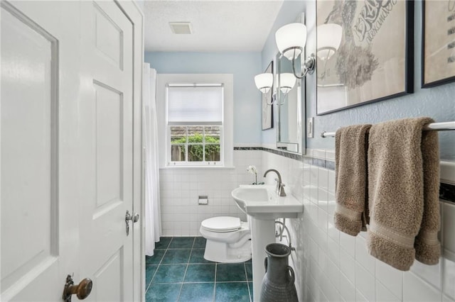 25 Standish Ave NW, Atlanta, GA 30309 - bathroom featuring tile patterned flooring, tile walls, toilet, and a wainscoted wall