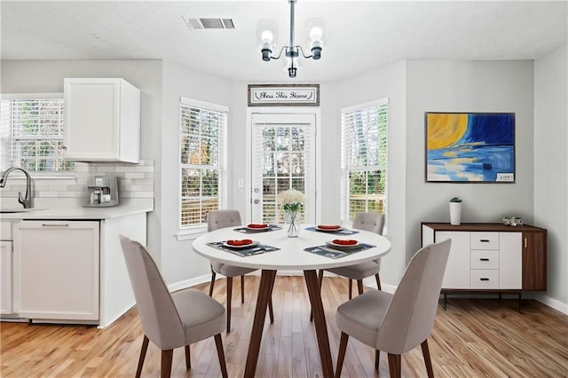 dining area with a notable chandelier, light hardwood / wood-style floors, and a healthy amount of sunlight