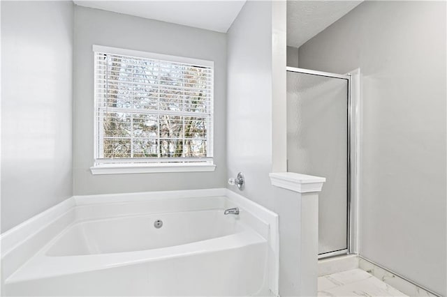 bathroom featuring a textured ceiling and shower with separate bathtub