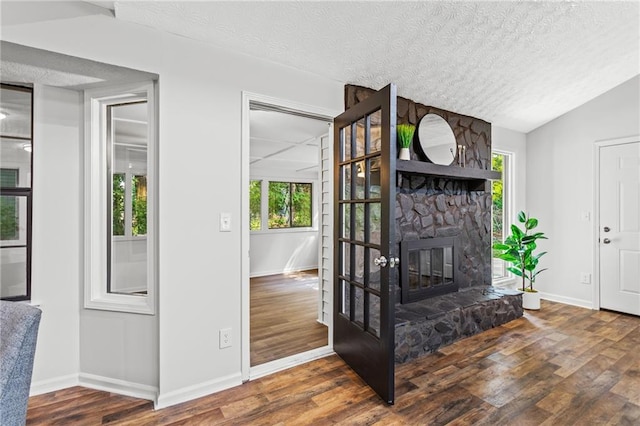 3833 Paddington Trl, Rex, GA 30273 - living room with wood finished floors, a textured ceiling, plenty of natural light, a stone fireplace, and vaulted ceiling
