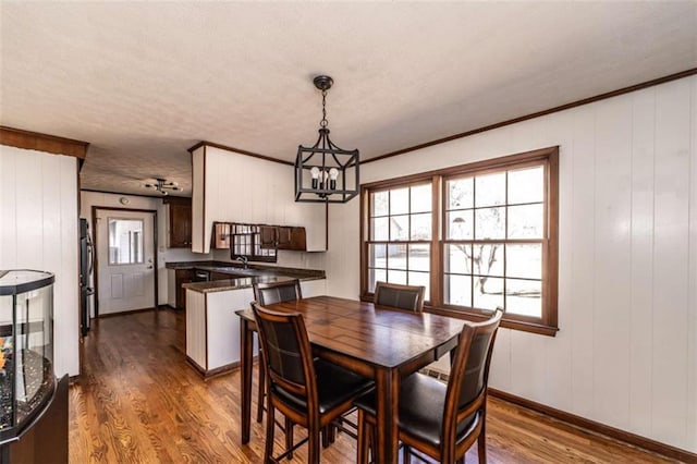 dining room with a textured ceiling, an inviting chandelier, dark wood-type flooring, and crown molding