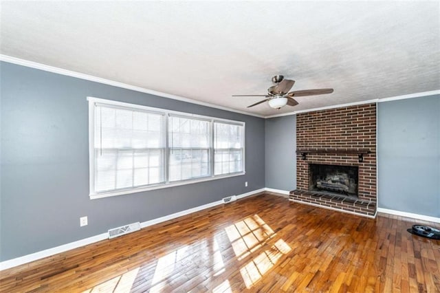 unfurnished living room with hardwood / wood-style flooring, a brick fireplace, ceiling fan, and crown molding