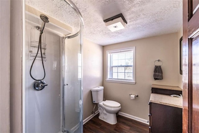 bathroom with wood-type flooring, a textured ceiling, toilet, vanity, and a shower with shower door