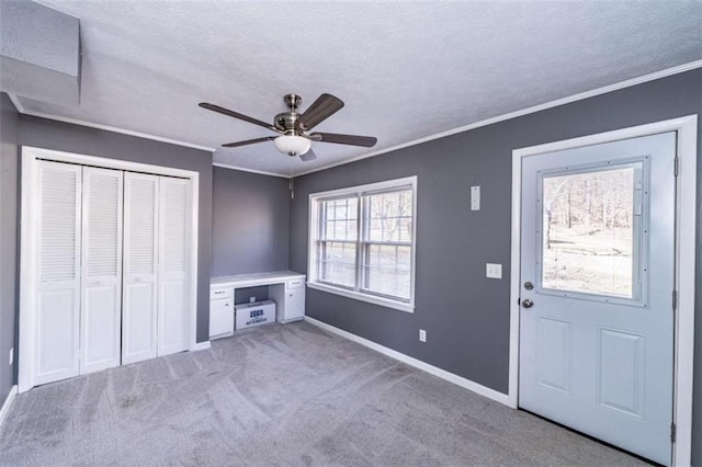 foyer featuring plenty of natural light, light colored carpet, ornamental molding, and a textured ceiling