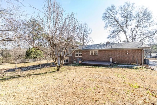 rear view of property featuring a lawn and a deck