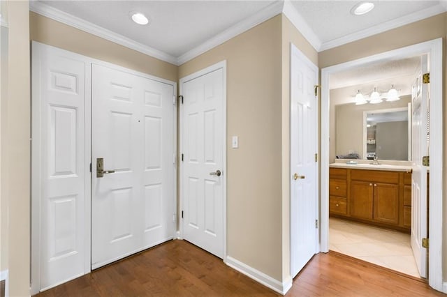 corridor featuring wood-type flooring, ornamental molding, and sink