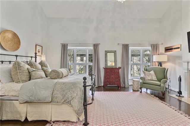 bedroom featuring multiple windows, dark wood-type flooring, and a high ceiling