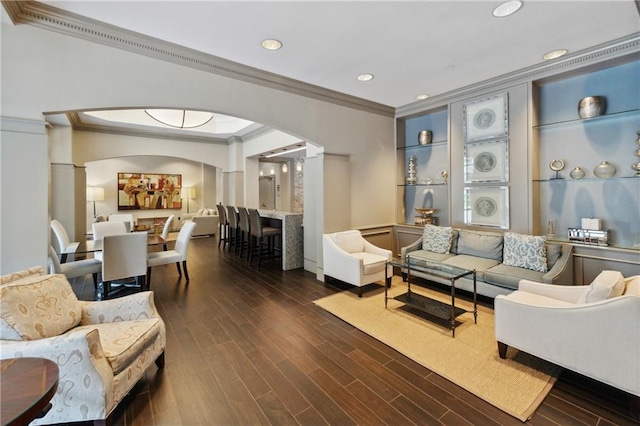 living room with dark wood-type flooring, crown molding, and built in shelves