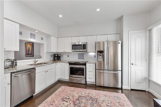 kitchen with light stone counters, appliances with stainless steel finishes, sink, and white cabinets