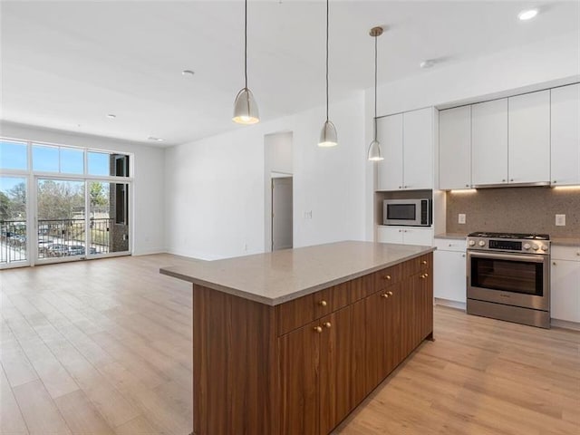 kitchen featuring decorative backsplash, open floor plan, a center island, stainless steel appliances, and white cabinetry