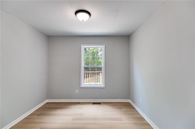 unfurnished room featuring baseboards, visible vents, and wood finished floors