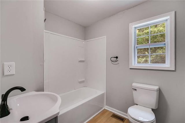 bathroom with a sink, visible vents, baseboards, toilet, and wood finished floors