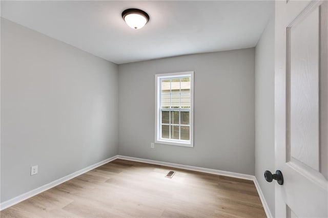 empty room featuring baseboards, visible vents, and wood finished floors