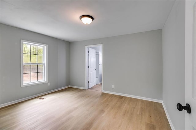 spare room featuring baseboards, light wood-type flooring, and visible vents