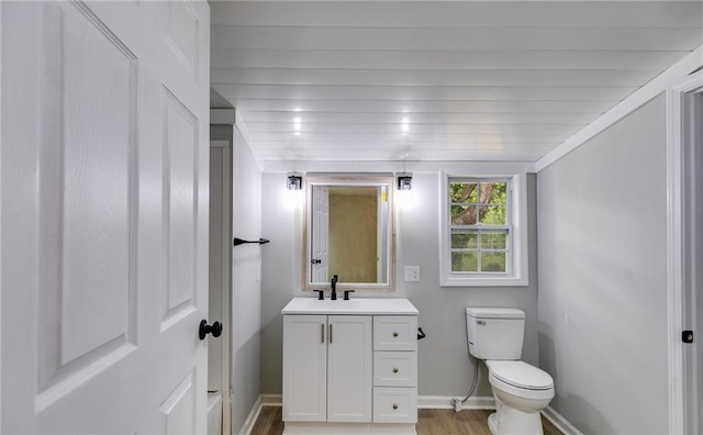 bathroom with wood finished floors, vanity, toilet, and baseboards