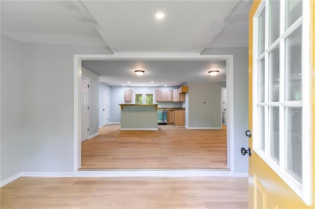 interior space featuring light wood-style flooring, open floor plan, and baseboards