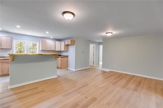 kitchen featuring a kitchen island, baseboards, open floor plan, recessed lighting, and light wood finished floors
