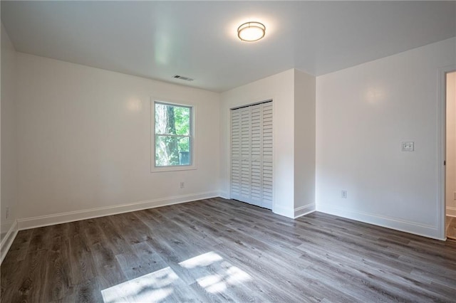 unfurnished bedroom featuring a closet and dark wood-type flooring