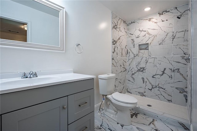 bathroom with vanity, toilet, and a tile shower