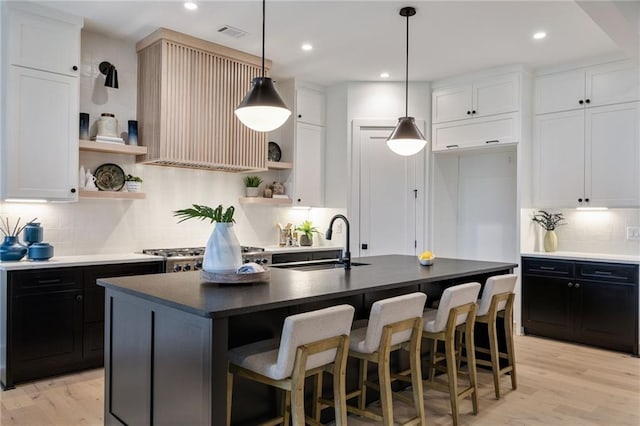 kitchen featuring white cabinetry, a center island with sink, and sink