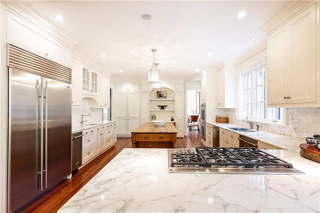 kitchen featuring dark wood finished floors, light stone countertops, stainless steel appliances, and a sink