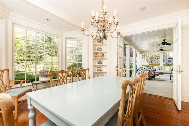 dining space with ceiling fan with notable chandelier, built in shelves, wood finished floors, and ornamental molding