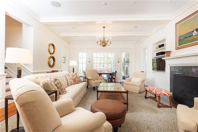 living room with built in features, beam ceiling, ornamental molding, and a high end fireplace