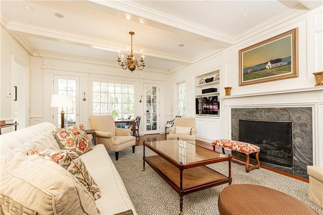 living room with beam ceiling, built in shelves, an inviting chandelier, and ornamental molding