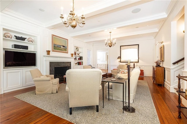 living room featuring a wainscoted wall, built in shelves, hardwood / wood-style flooring, an inviting chandelier, and crown molding