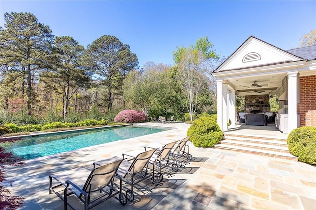 outdoor pool featuring exterior fireplace, a ceiling fan, and a patio area