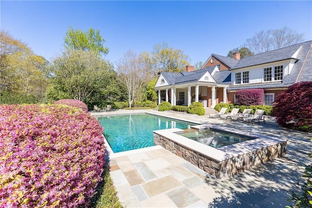 view of swimming pool with a patio area and a pool with connected hot tub