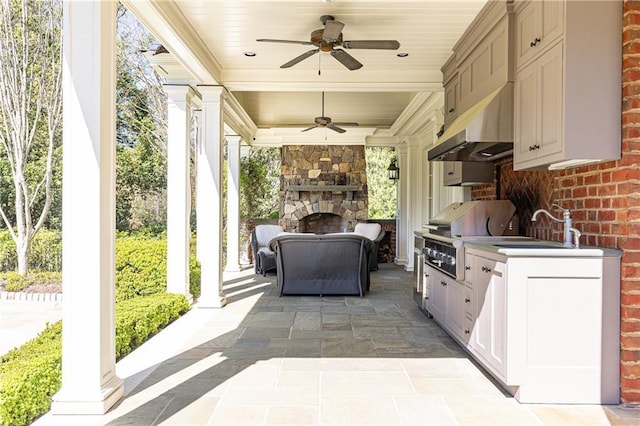 view of patio / terrace featuring exterior kitchen, ceiling fan, a sink, an outdoor stone fireplace, and grilling area