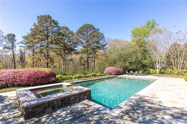 outdoor pool with an in ground hot tub and a patio area