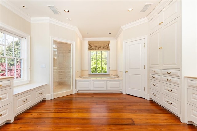 unfurnished bedroom with visible vents, ensuite bath, ornamental molding, and hardwood / wood-style flooring