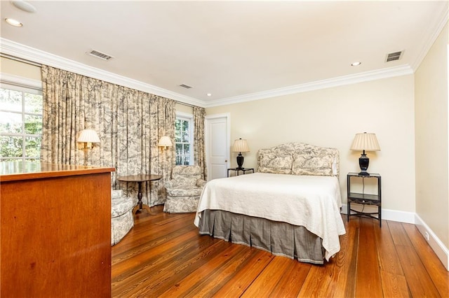 bedroom featuring visible vents, wood-type flooring, baseboards, and crown molding