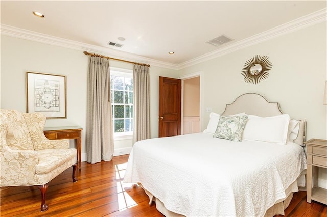 bedroom with hardwood / wood-style flooring, crown molding, and visible vents