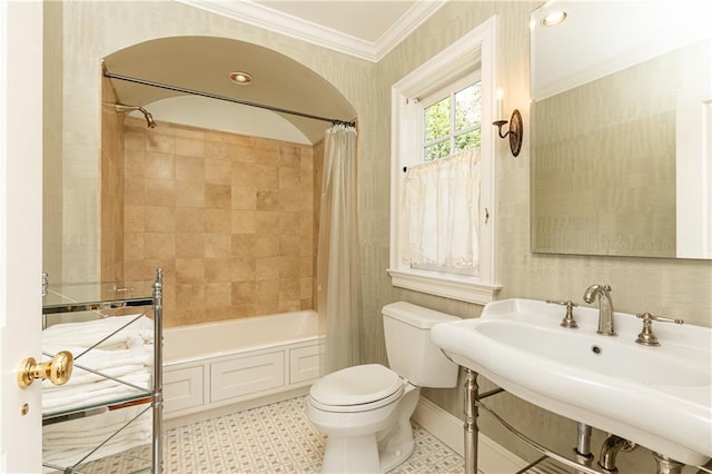 bathroom featuring shower / bathtub combination with curtain, wallpapered walls, a sink, ornamental molding, and toilet