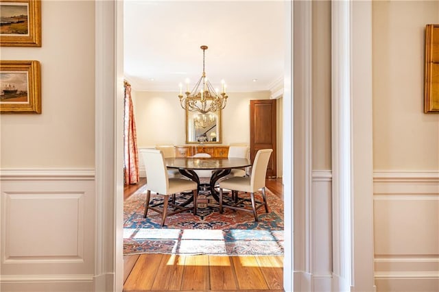 dining room featuring a notable chandelier, ornamental molding, and wood finished floors